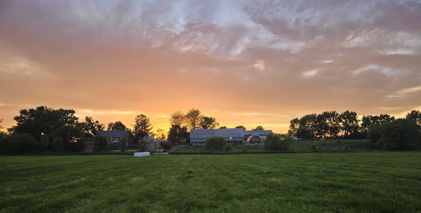 Sunset over the farmhouse, barn and green pastures at Faithful Valley Farms